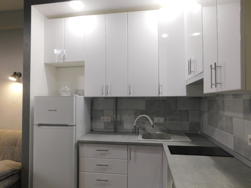 This is an example of a mid-sized industrial l-shaped eat-in kitchen in Other with white cabinets, wood benchtops, grey splashback, porcelain floors, no island, grey floor and grey benchtop.