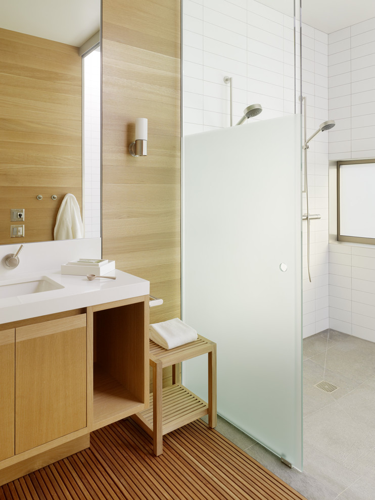 Photo of a scandinavian bathroom in San Francisco with an undermount sink, flat-panel cabinets, white tile, concrete floors, medium wood cabinets and a double shower.