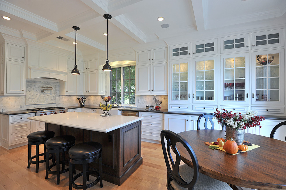 Large traditional u-shaped eat-in kitchen in Los Angeles with a farmhouse sink, glass-front cabinets, white cabinets, quartz benchtops, grey splashback, stainless steel appliances, light hardwood floors and with island.