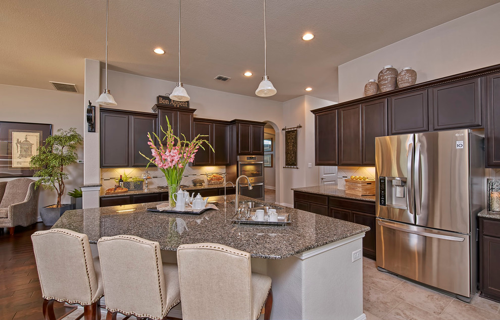 Large traditional l-shaped eat-in kitchen in San Diego with a double-bowl sink, shaker cabinets, brown cabinets, granite benchtops, beige splashback, cement tile splashback, stainless steel appliances, marble floors and with island.