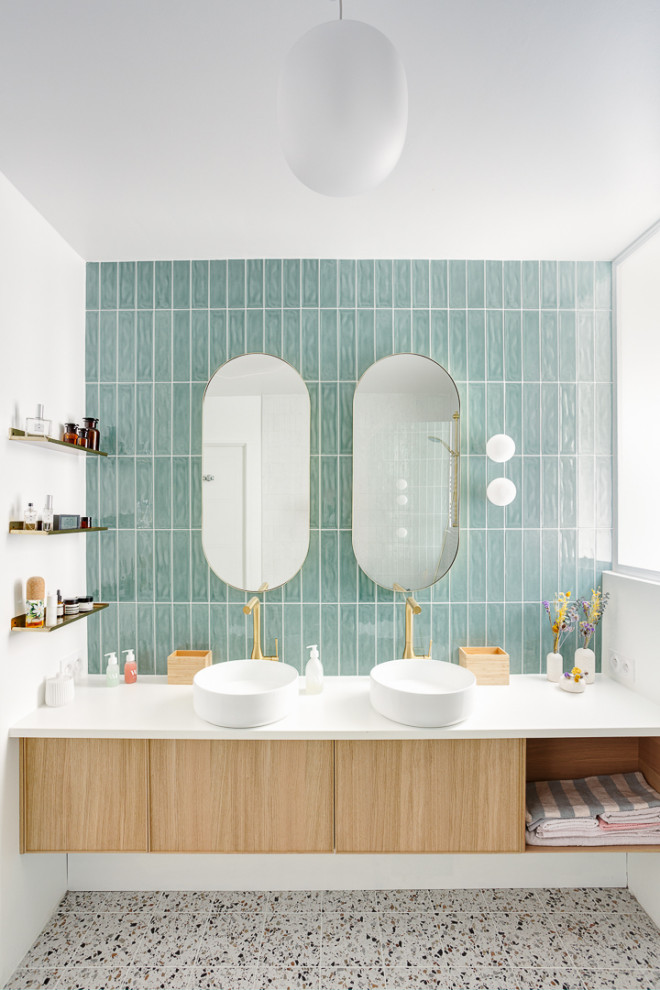 This is an example of a mid-sized contemporary master bathroom in Paris with beaded inset cabinets, light wood cabinets, a freestanding tub, a shower/bathtub combo, green tile, terra-cotta tile, white walls, terrazzo floors, a vessel sink, quartzite benchtops, multi-coloured floor, a hinged shower door, white benchtops, a laundry, a double vanity and a floating vanity.