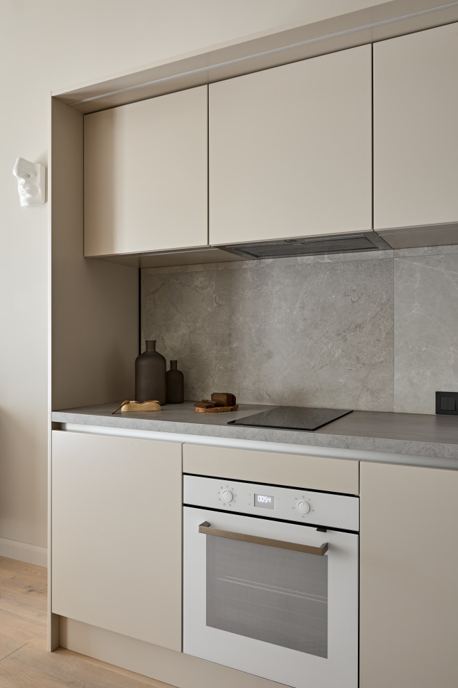 This is an example of a small contemporary single-wall eat-in kitchen in Saint Petersburg with a single-bowl sink, flat-panel cabinets, beige cabinets, wood benchtops, grey splashback, porcelain splashback, white appliances, medium hardwood floors, brown floor and grey benchtop.