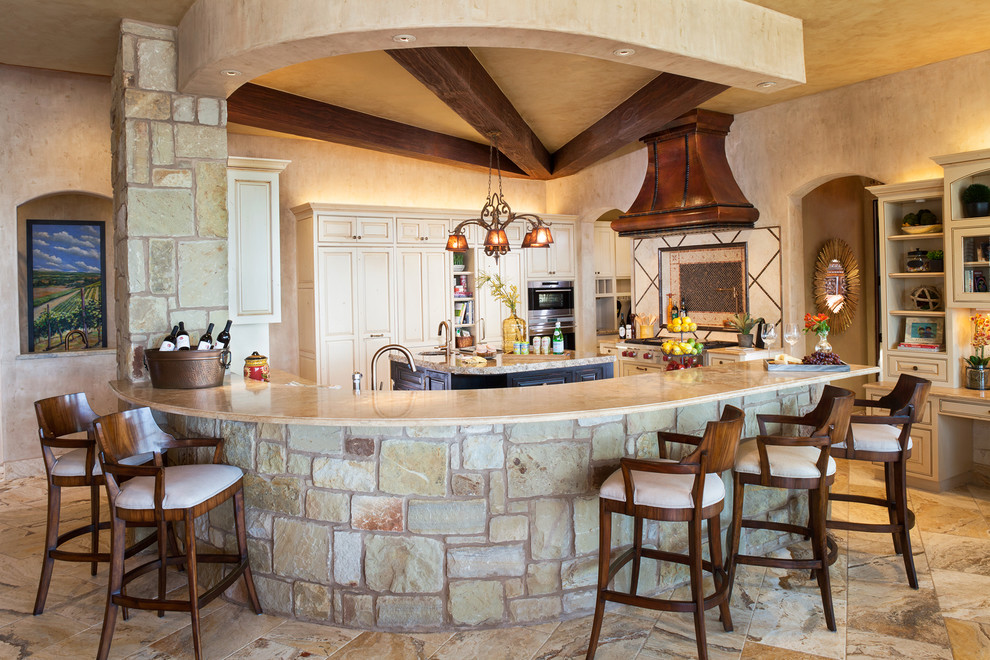 Photo of a large mediterranean u-shaped eat-in kitchen in Austin with raised-panel cabinets, beige cabinets, granite benchtops, beige splashback, ceramic splashback, stainless steel appliances, travertine floors and with island.