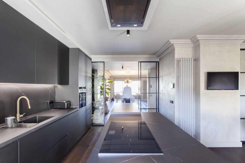 Bohemian grey and black single-wall kitchen/diner in Madrid with an integrated sink, flat-panel cabinets, grey cabinets, marble worktops, grey splashback, marble splashback, integrated appliances, dark hardwood flooring, an island, brown floors and grey worktops.
