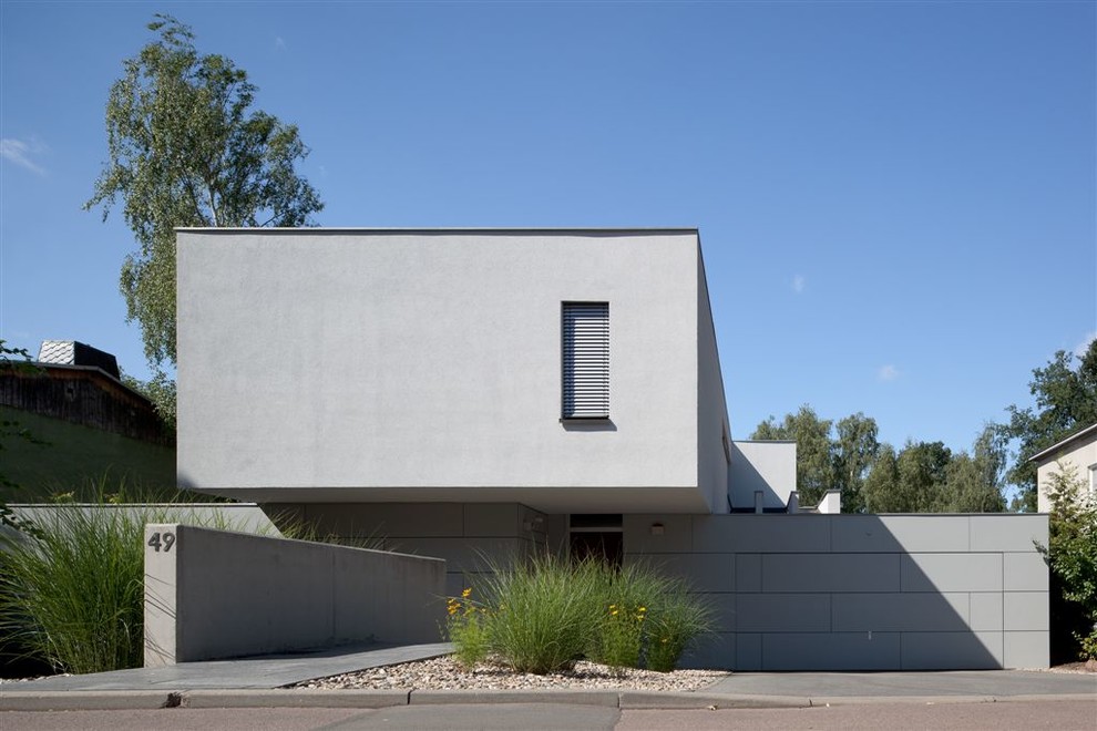 This is an example of a mid-sized modern two-storey concrete grey exterior in Leipzig with a flat roof.