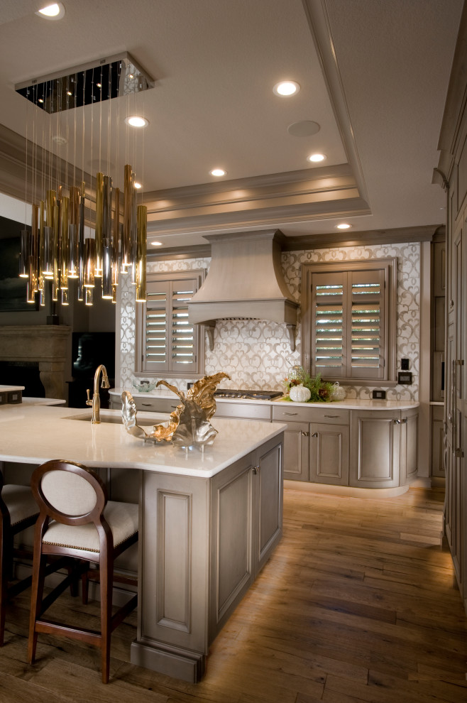 This is an example of a large traditional open plan kitchen in Wichita with a single-bowl sink, recessed-panel cabinets, beige cabinets, quartz benchtops, beige splashback, porcelain splashback, panelled appliances, medium hardwood floors, with island, brown floor and white benchtop.
