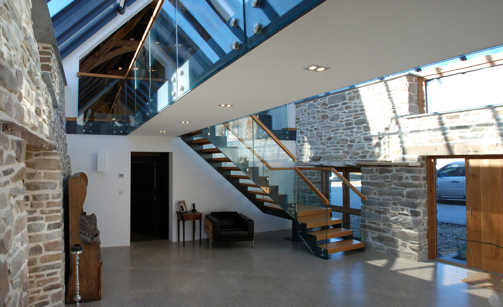 This is an example of an expansive contemporary entry hall in Cornwall with concrete floors, a medium wood front door, a single front door, grey floor and vaulted.