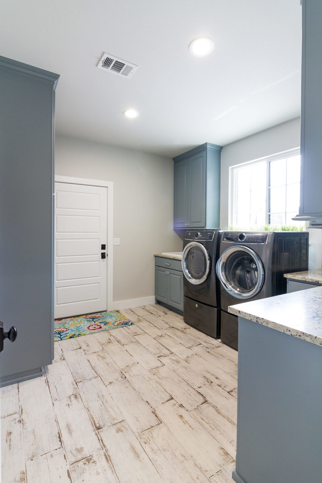 Inspiration for a country utility room in Other with blue cabinets, granite benchtops, grey walls, porcelain floors, a side-by-side washer and dryer and grey floor.