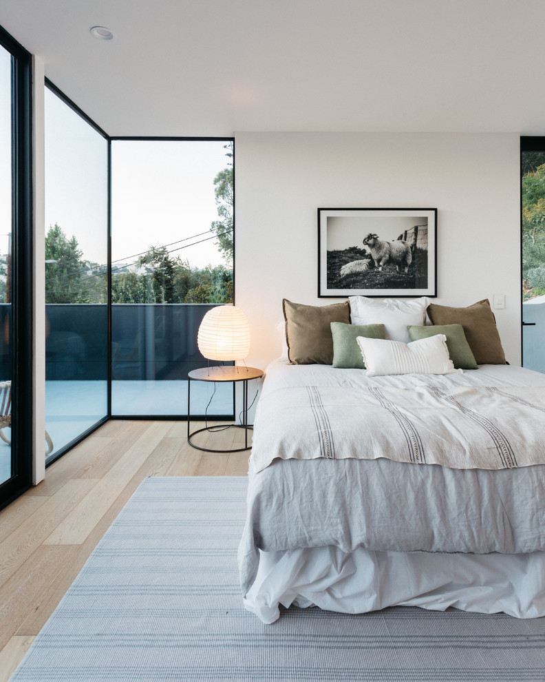 This is an example of a mid-sized modern master bedroom in Los Angeles with white walls and light hardwood floors.