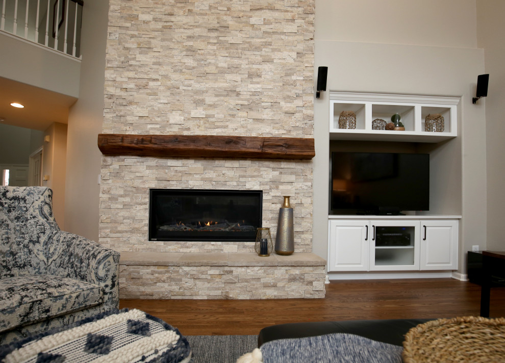 Photo of a mid-sized beach style open concept family room in Denver with beige walls, dark hardwood floors, a standard fireplace, a stone fireplace surround, a freestanding tv and brown floor.