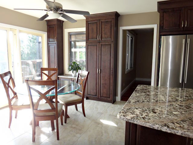 Large transitional u-shaped porcelain tile kitchen photo in Toronto with raised-panel cabinets, dark wood cabinets, granite countertops and an island