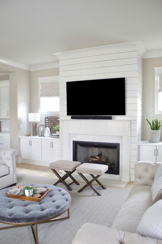 Inspiration for a large contemporary open concept living room in Nashville with beige walls, light hardwood floors, a standard fireplace, a wall-mounted tv and beige floor.