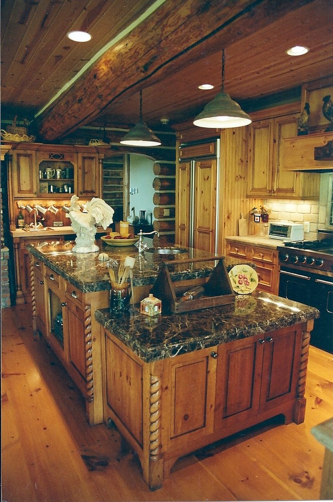 Example of a light wood floor kitchen design with an undermount sink, granite countertops, stone tile backsplash and two islands