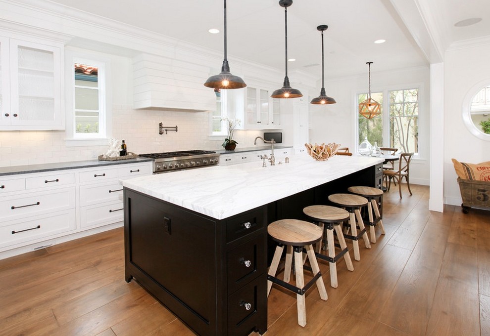 Inspiration for a large rustic galley medium tone wood floor eat-in kitchen remodel with a farmhouse sink, shaker cabinets, white cabinets, marble countertops, white backsplash, subway tile backsplash, stainless steel appliances and an island