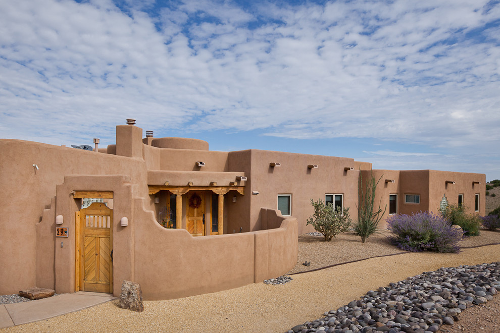 This is an example of a one-storey stucco brown house exterior in Albuquerque with a flat roof.