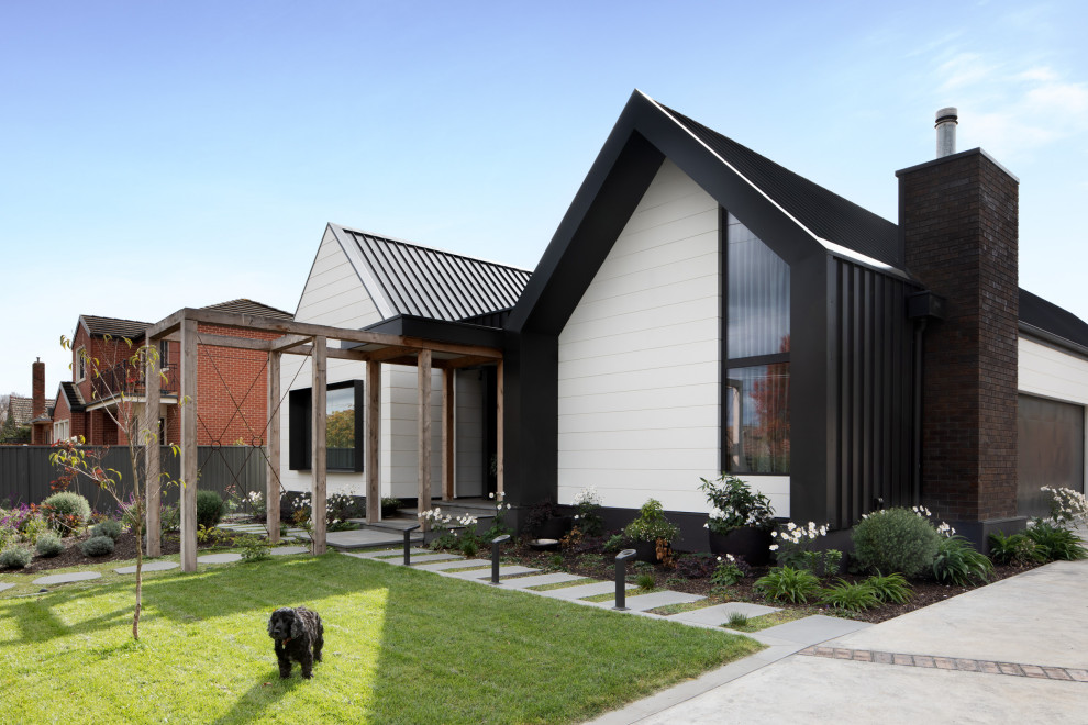 Exemple d'une très grande façade de maison tendance de plain-pied avec un toit à deux pans, un toit en métal et un toit noir.