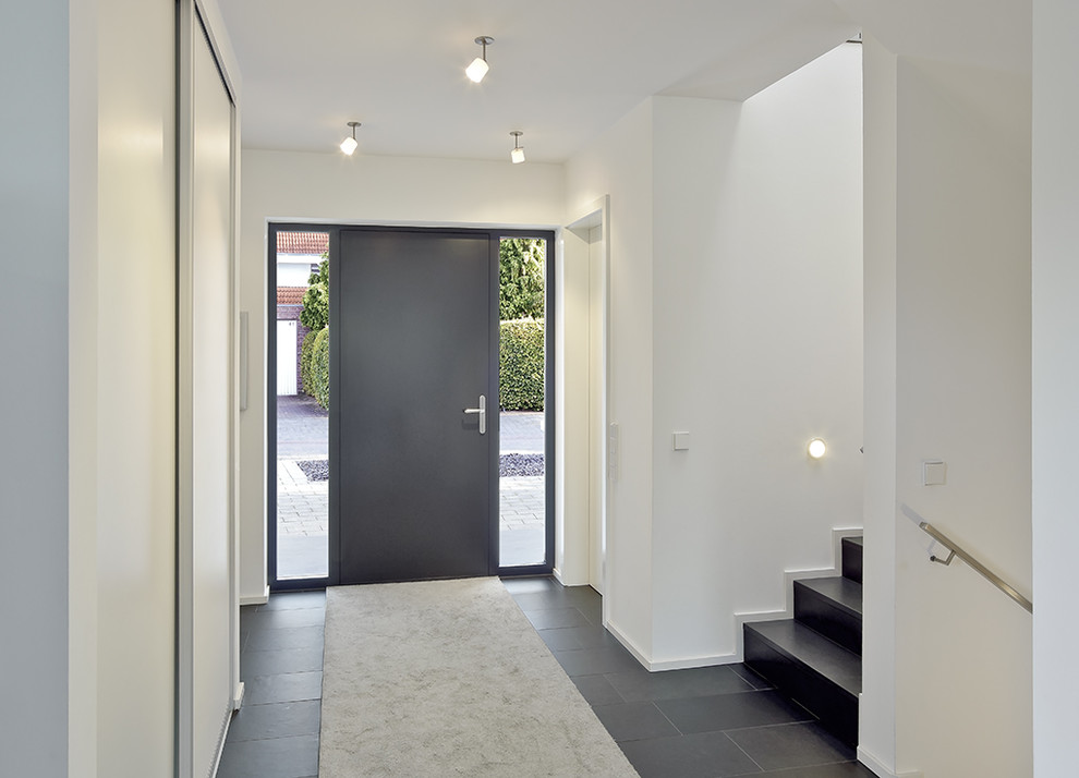 This is an example of a mid-sized contemporary entry hall in Other with white walls, a single front door, a gray front door and concrete floors.