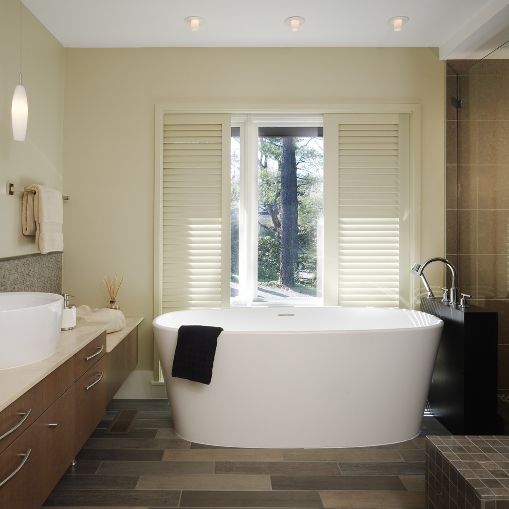 Design ideas for a mid-sized contemporary master bathroom in DC Metro with a vessel sink, flat-panel cabinets, a freestanding tub, beige tile, porcelain tile, beige walls, porcelain floors and dark wood cabinets.