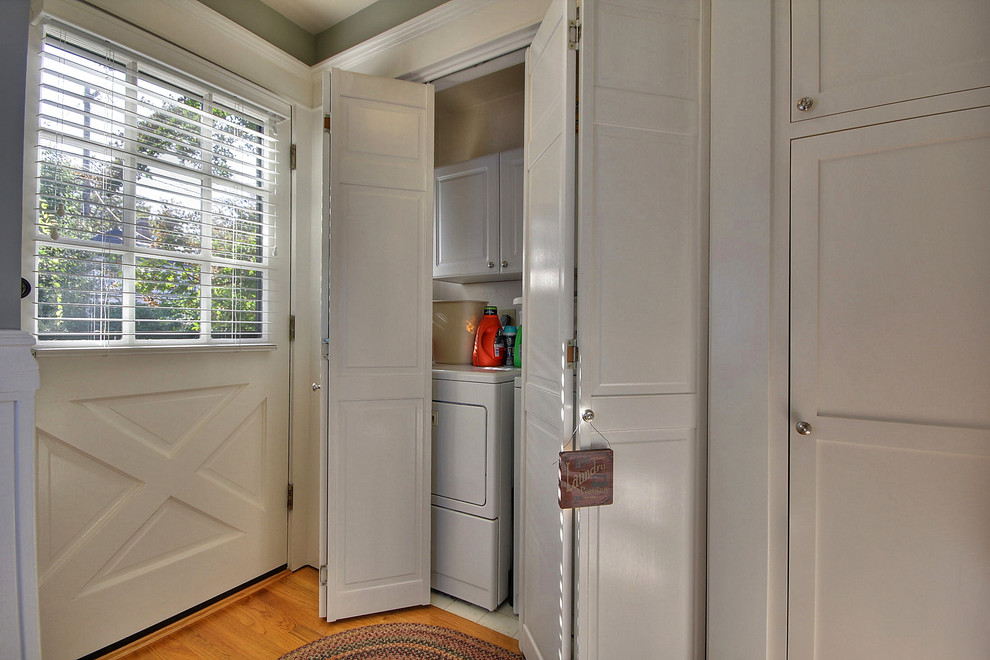 Photo of a small arts and crafts single-wall laundry cupboard in San Francisco with raised-panel cabinets, white cabinets, beige walls and a side-by-side washer and dryer.
