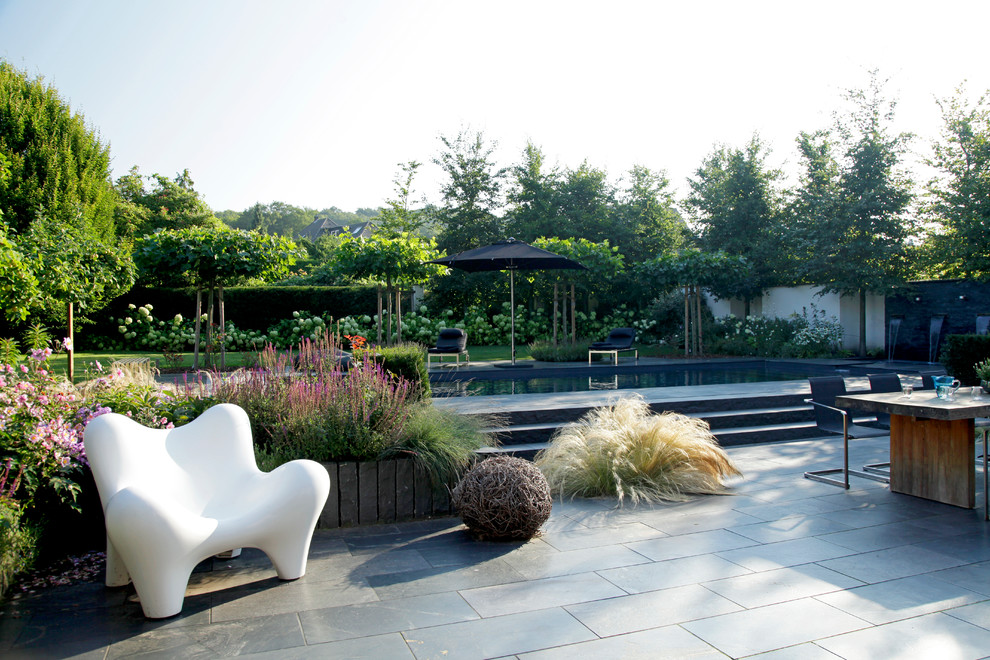 Großes Modernes Poolhaus neben dem Haus in rechteckiger Form mit Natursteinplatten in Sonstige