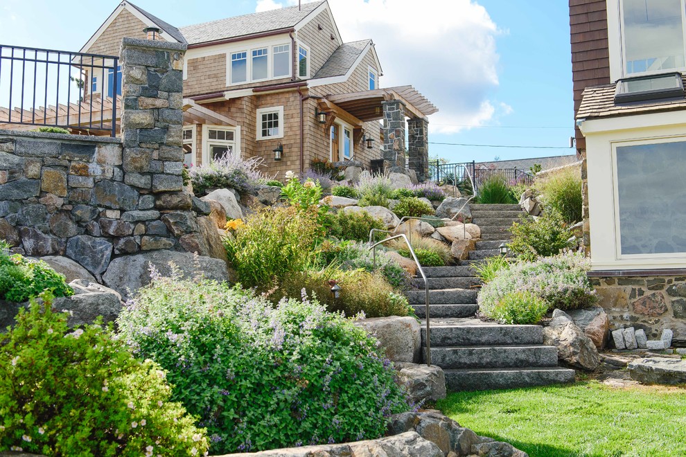 This is an example of a mid-sized beach style backyard garden in Boston with a retaining wall and natural stone pavers.