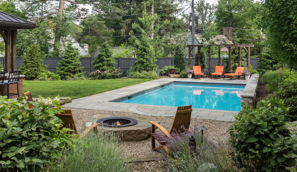 Design ideas for a mid-sized traditional backyard rectangular lap pool in Cleveland with a water feature and natural stone pavers.
