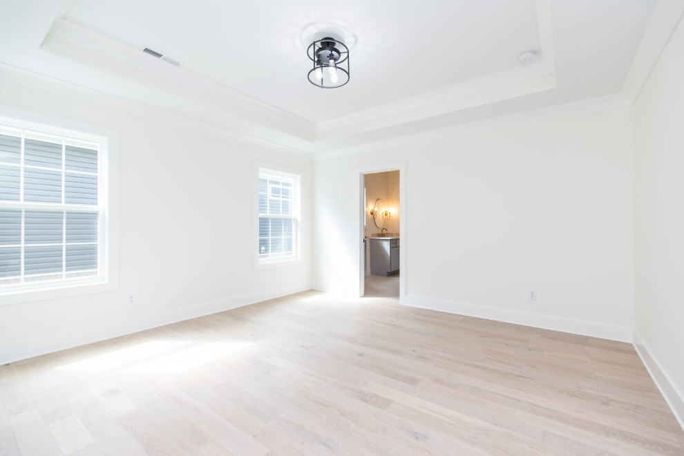 This is an example of a coastal master bedroom in Other with white walls, light hardwood flooring, no fireplace, beige floors and a drop ceiling.