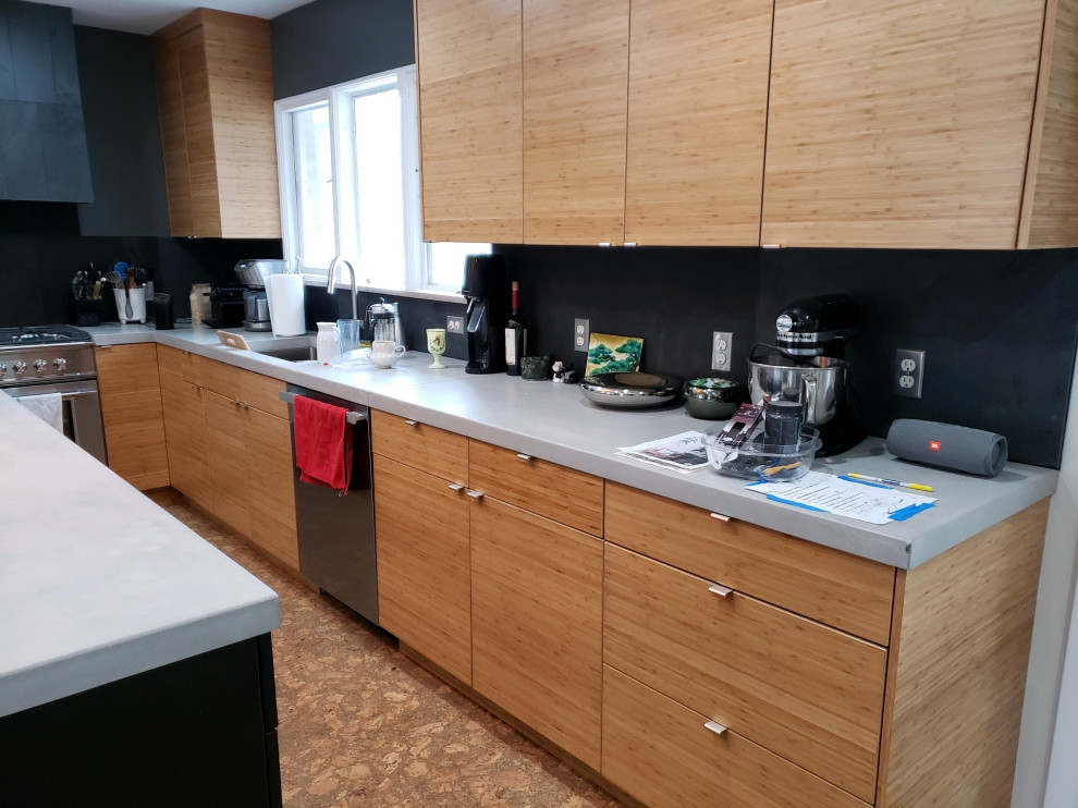 Midcentury kitchen in Grand Rapids with flat-panel cabinets, medium wood cabinets, concrete benchtops, black splashback, slate splashback, stainless steel appliances, with island and grey benchtop.