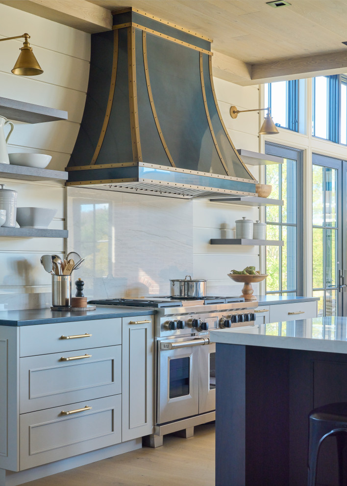 Photo of an industrial u-shaped open plan kitchen in New York with a farmhouse sink, recessed-panel cabinets, blue cabinets, quartz benchtops, white splashback, shiplap splashback, stainless steel appliances, light hardwood floors, multiple islands, beige floor, white benchtop and wood.