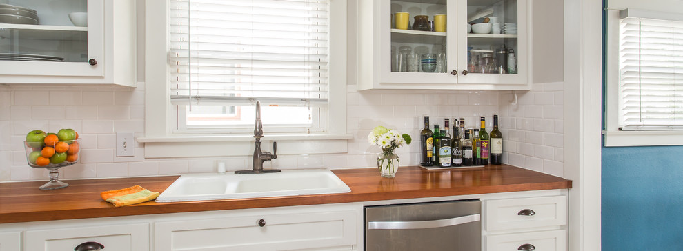 Inspiration for a mid-sized transitional galley medium tone wood floor enclosed kitchen remodel in Santa Barbara with a drop-in sink, shaker cabinets, white cabinets, white backsplash, ceramic backsplash and stainless steel appliances