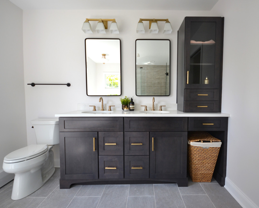 Design ideas for a large traditional ensuite bathroom in Philadelphia with shaker cabinets, dark wood cabinets, a freestanding bath, a corner shower, a one-piece toilet, white walls, vinyl flooring, a submerged sink, engineered stone worktops, grey floors, a hinged door, white worktops, a shower bench, double sinks and a built in vanity unit.