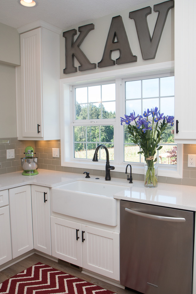 Large country u-shaped separate kitchen in Portland with a farmhouse sink, grey splashback, stainless steel appliances, a peninsula, louvered cabinets, white cabinets, quartz benchtops, ceramic splashback, vinyl floors and brown floor.