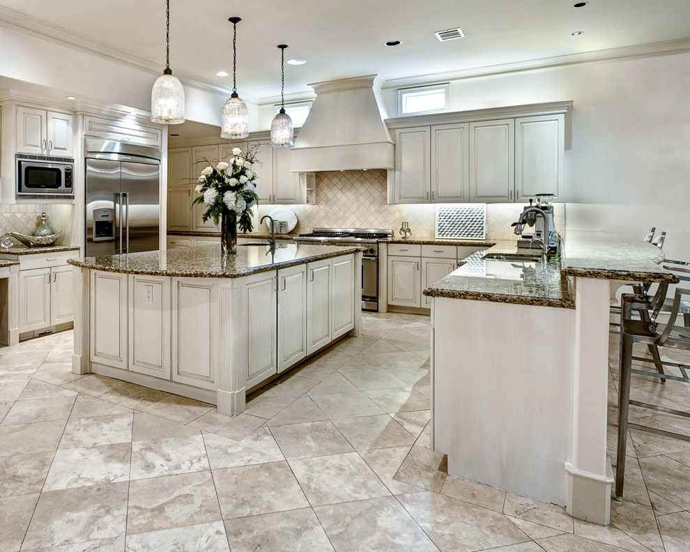 Example of a transitional marble floor open concept kitchen design in Houston with a double-bowl sink, shaker cabinets, white cabinets, marble countertops, beige backsplash, stone slab backsplash, stainless steel appliances and an island