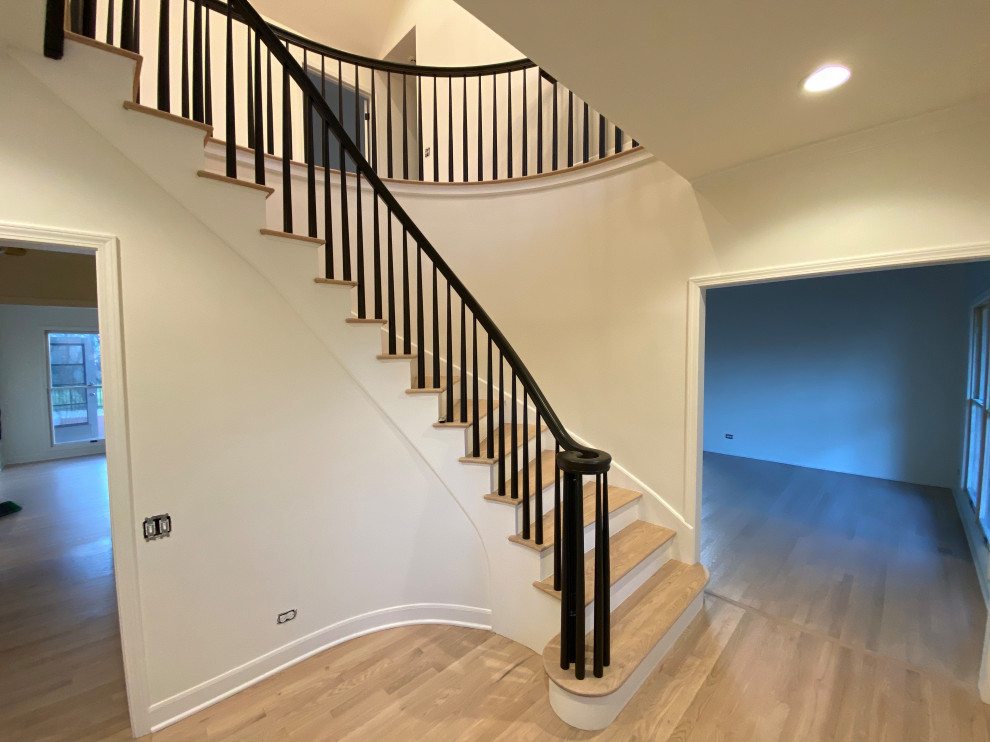 Cette photo montre un grand escalier peint courbe moderne en bois avec des marches en bois, un garde-corps en bois et palier.