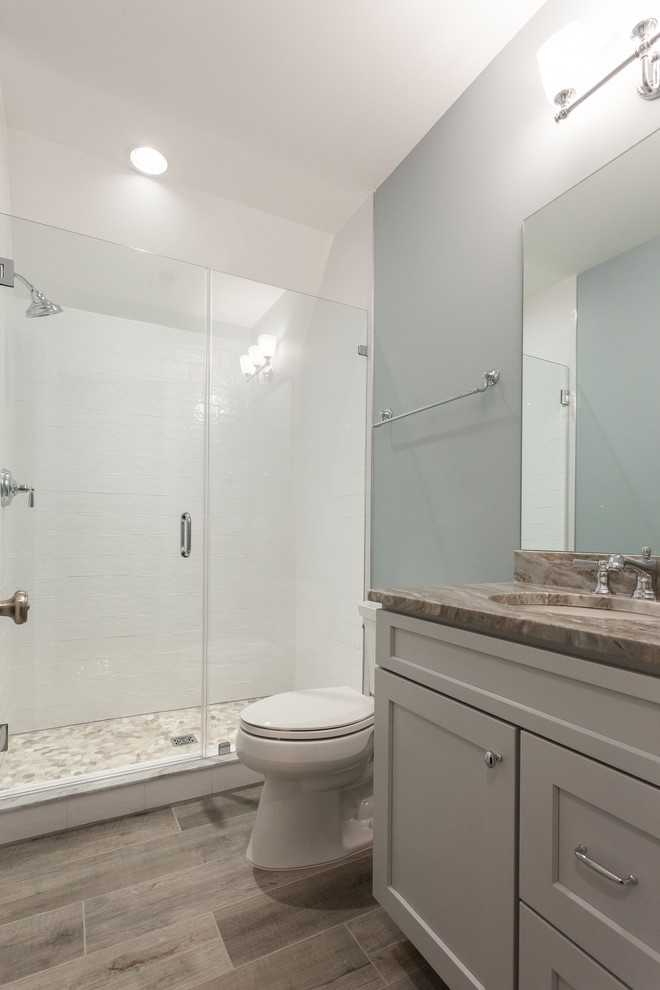 Design ideas for a country bathroom in DC Metro with shaker cabinets, grey cabinets, an alcove shower, a two-piece toilet, white tile, subway tile, blue walls, porcelain floors, an undermount sink, granite benchtops, brown floor, a hinged shower door and beige benchtops.