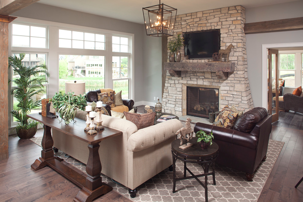 Traditional living room in Minneapolis with grey walls, dark hardwood floors, a two-sided fireplace, a stone fireplace surround and a wall-mounted tv.