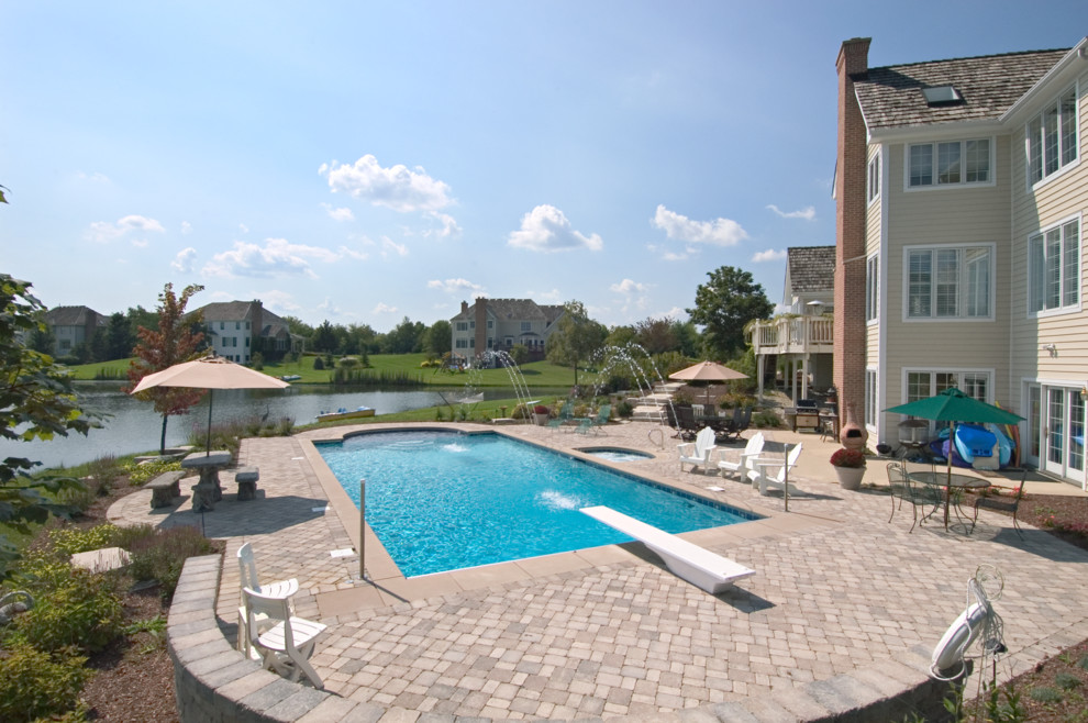 Photo of a large traditional backyard rectangular lap pool in Chicago with a hot tub and concrete pavers.