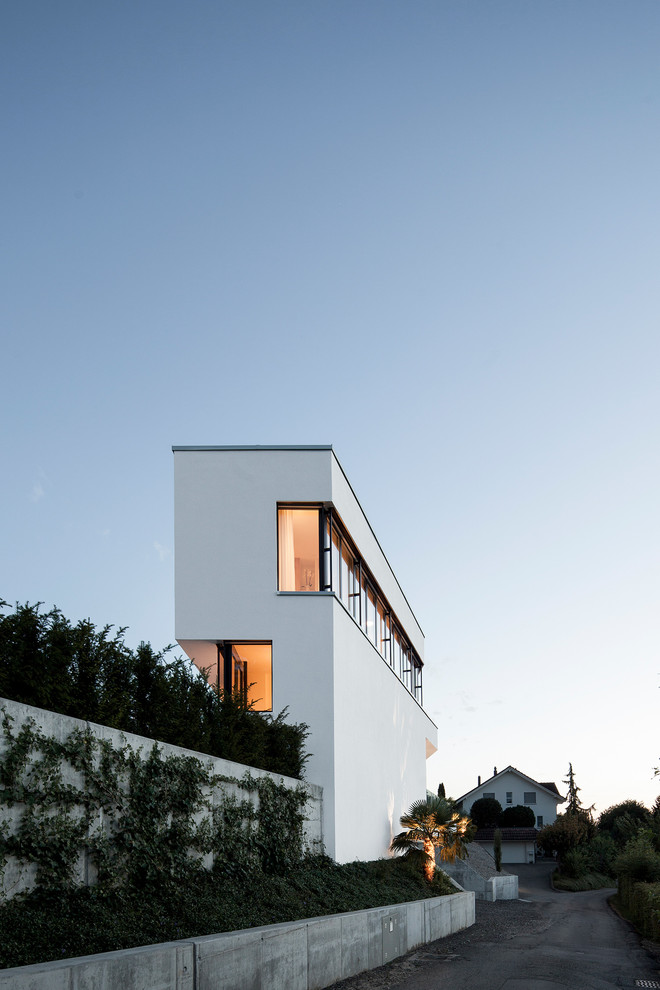 This is an example of an expansive modern three-storey stucco white house exterior in Other with a flat roof.