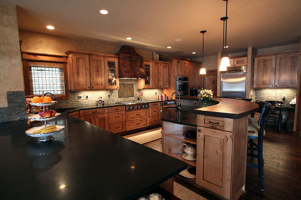 Large mountain style u-shaped medium tone wood floor eat-in kitchen photo in Seattle with an undermount sink, shaker cabinets, medium tone wood cabinets, solid surface countertops, multicolored backsplash, mosaic tile backsplash, stainless steel appliances and two islands