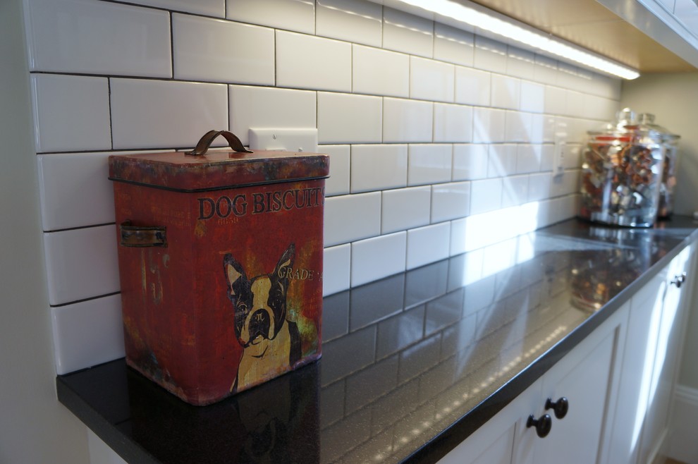 Inspiration for a small rustic l-shaped light wood floor and beige floor enclosed kitchen remodel in Boston with an undermount sink, recessed-panel cabinets, white cabinets, granite countertops, white backsplash, subway tile backsplash, stainless steel appliances, an island and black countertops