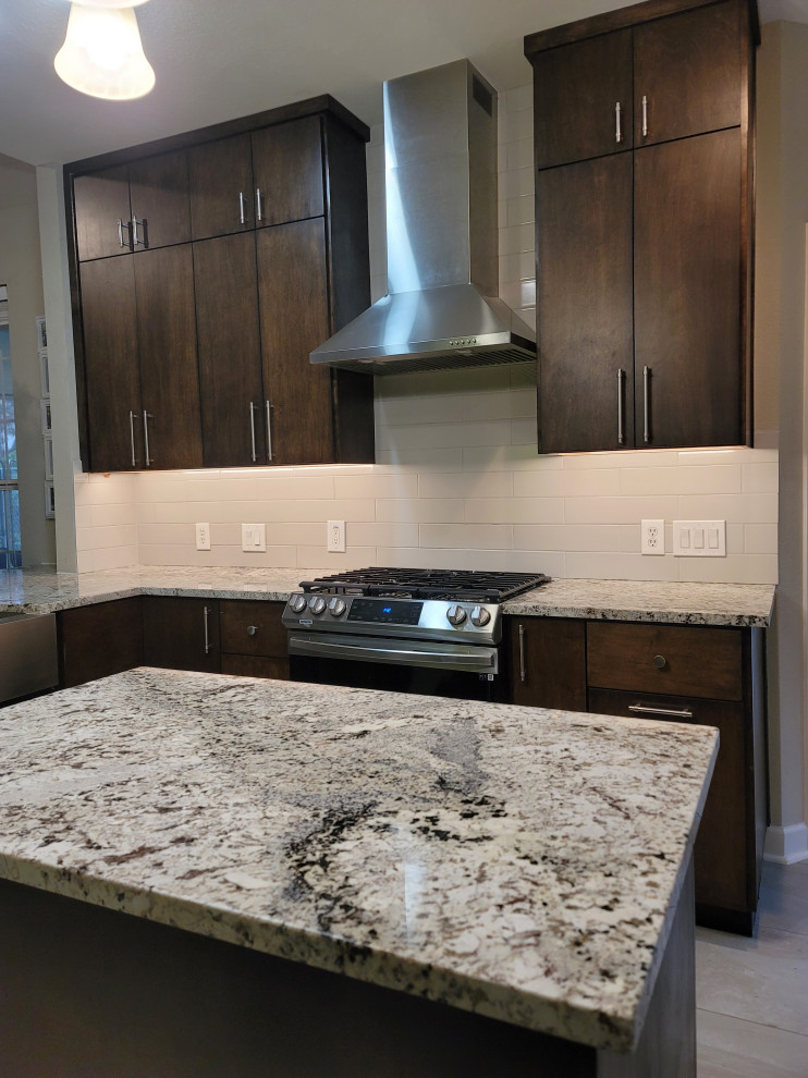 This is an example of a mid-sized midcentury u-shaped eat-in kitchen in Austin with a farmhouse sink, flat-panel cabinets, dark wood cabinets, granite benchtops, grey splashback, ceramic splashback, stainless steel appliances, porcelain floors, with island, beige floor and beige benchtop.