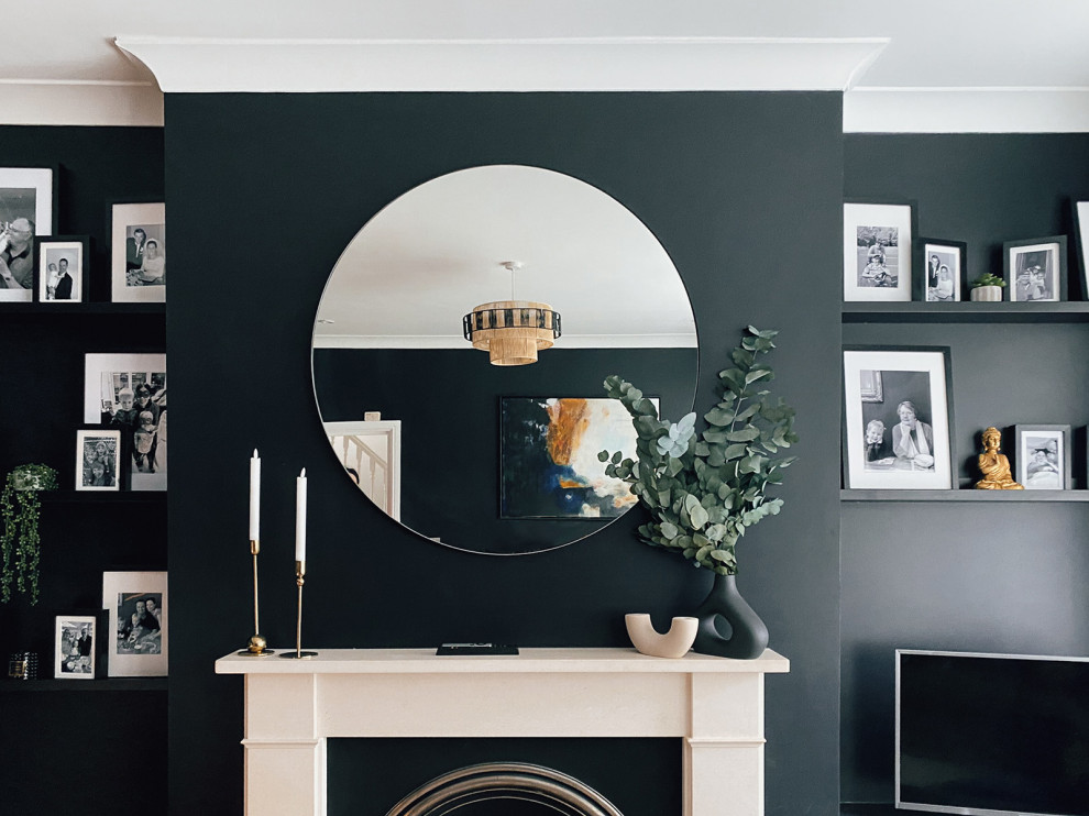 Inspiration pour un salon bohème de taille moyenne et fermé avec un mur noir, un sol en bois brun, une cheminée standard, un manteau de cheminée en pierre, un téléviseur indépendant et un sol gris.