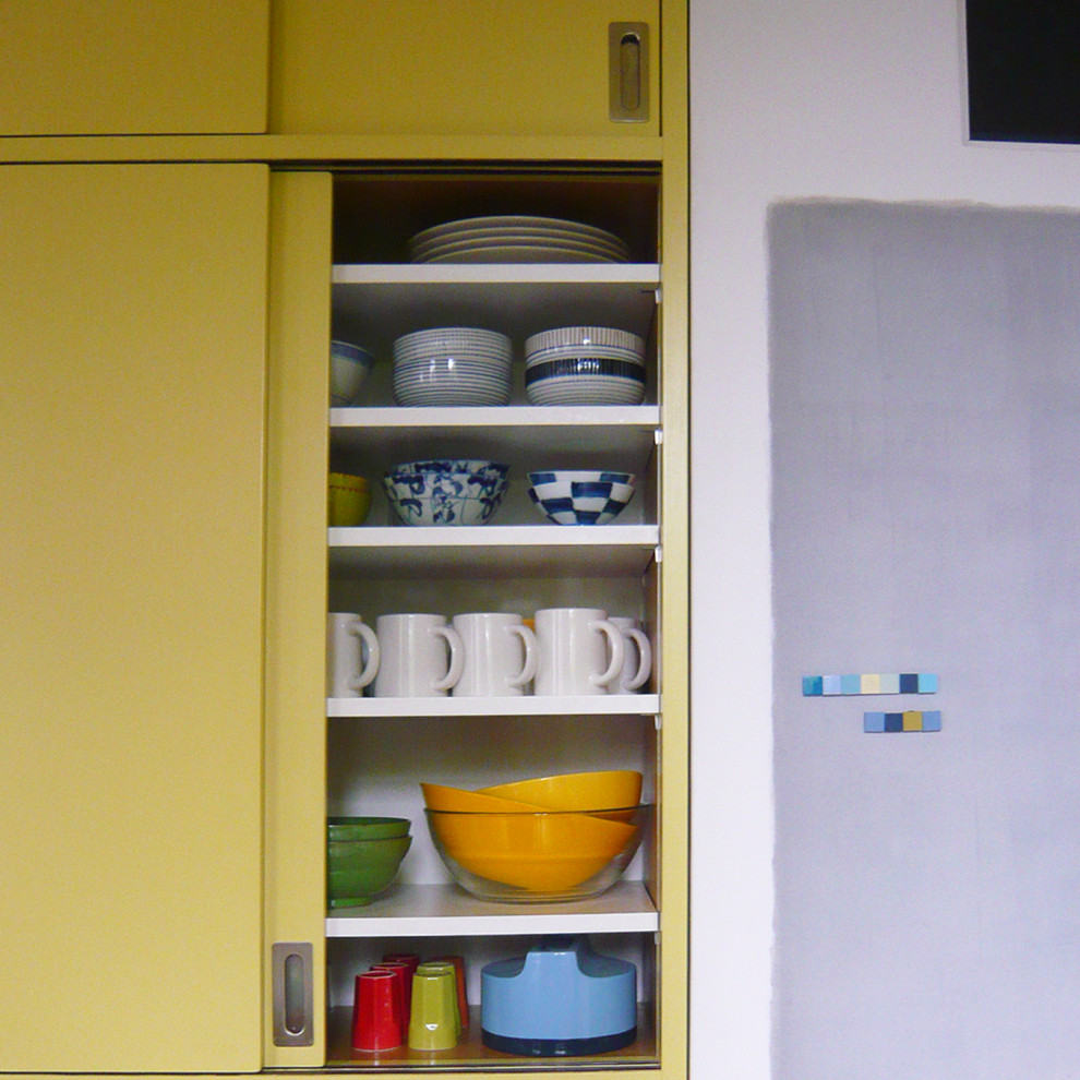 Modelo de cocinas en U de estilo americano de tamaño medio abierto con armarios con paneles lisos, puertas de armario amarillas, encimera de laminado, salpicadero con efecto espejo, suelo de azulejos de cemento, suelo negro y encimeras negras