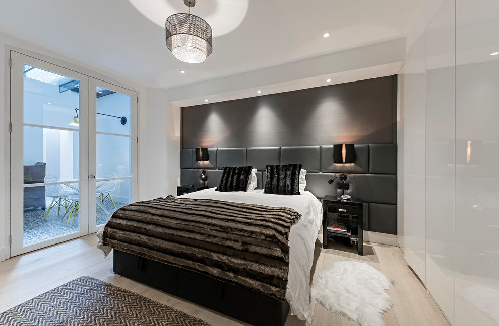 This is an example of a mid-sized contemporary bedroom in London with white walls, light hardwood floors and beige floor.