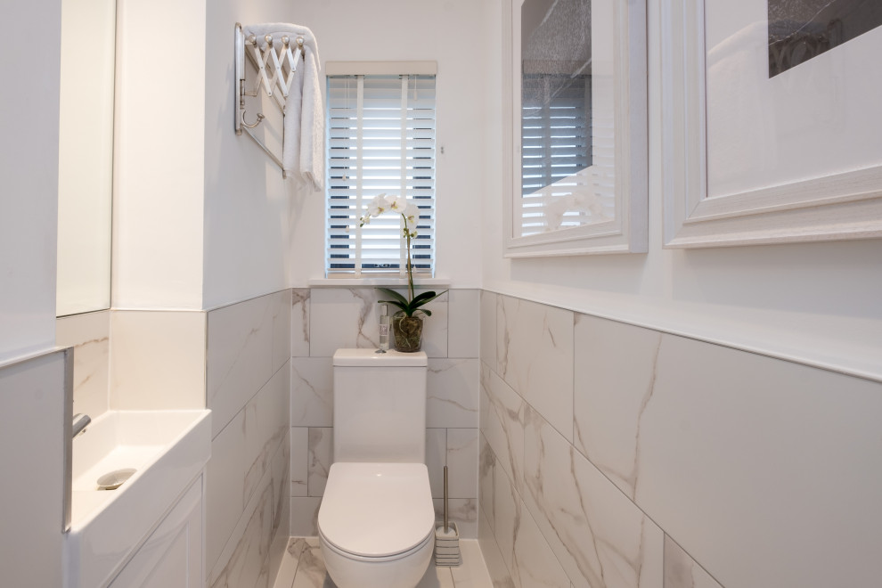 Cette image montre une petite salle de bain marine avec un placard à porte shaker, des portes de placard blanches, WC à poser, un mur blanc, sol en stratifié, un plan de toilette blanc, meuble simple vasque et meuble-lavabo sur pied.