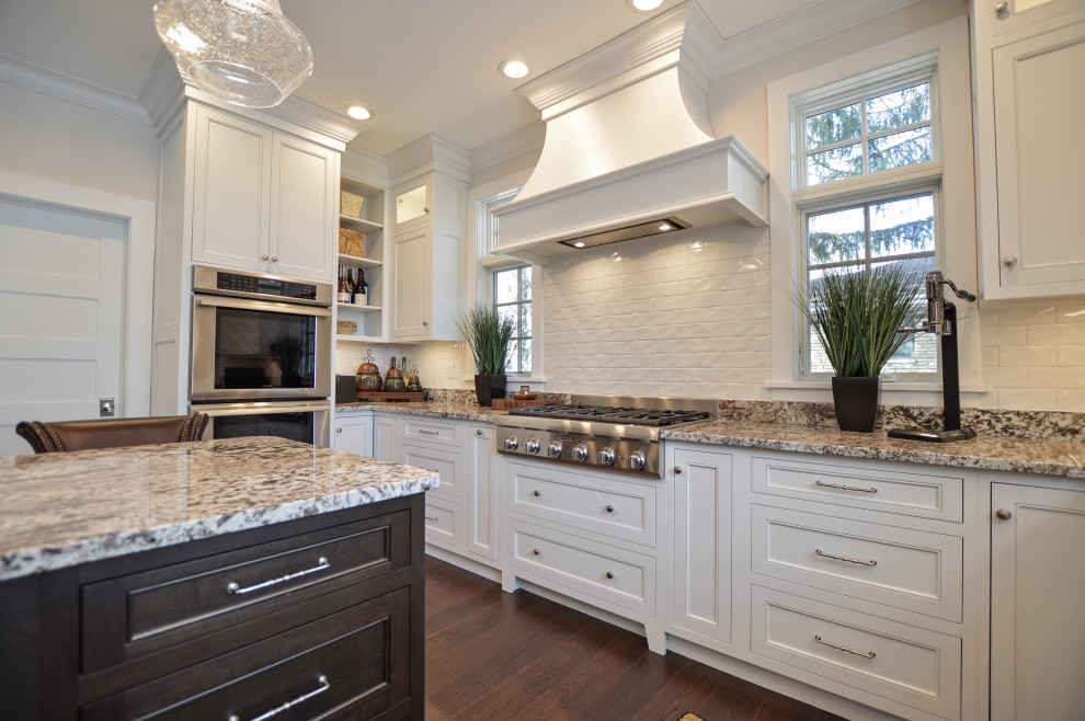 Inspiration for a transitional dark wood floor and brown floor eat-in kitchen remodel with an undermount sink, shaker cabinets, white cabinets, granite countertops, white backsplash, ceramic backsplash, stainless steel appliances, an island and beige countertops