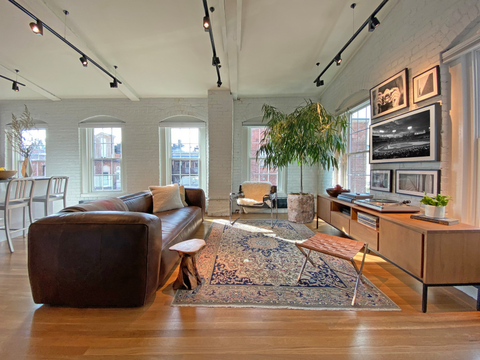 Inspiration for a small contemporary loft-style medium tone wood floor, exposed beam and brick wall living room remodel in Boston with white walls, no fireplace and a wall-mounted tv