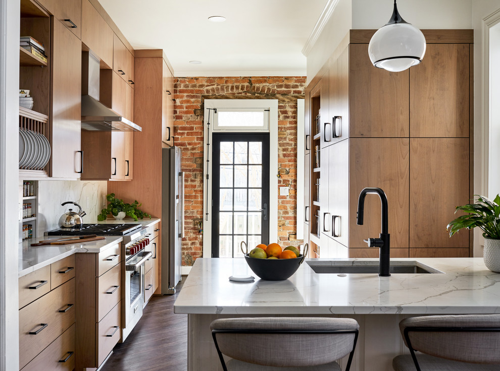 Mid-sized transitional eat-in kitchen in DC Metro with beige cabinets, white splashback, stainless steel appliances, a peninsula and white benchtop.