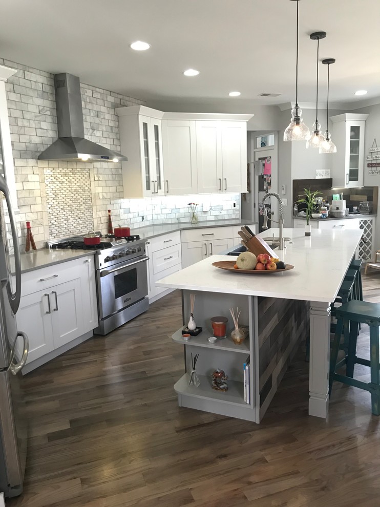 Inspiration for a large transitional single-wall light wood floor and gray floor eat-in kitchen remodel in Atlanta with a farmhouse sink, shaker cabinets, white cabinets, quartzite countertops, white backsplash, marble backsplash, stainless steel appliances, an island and white countertops