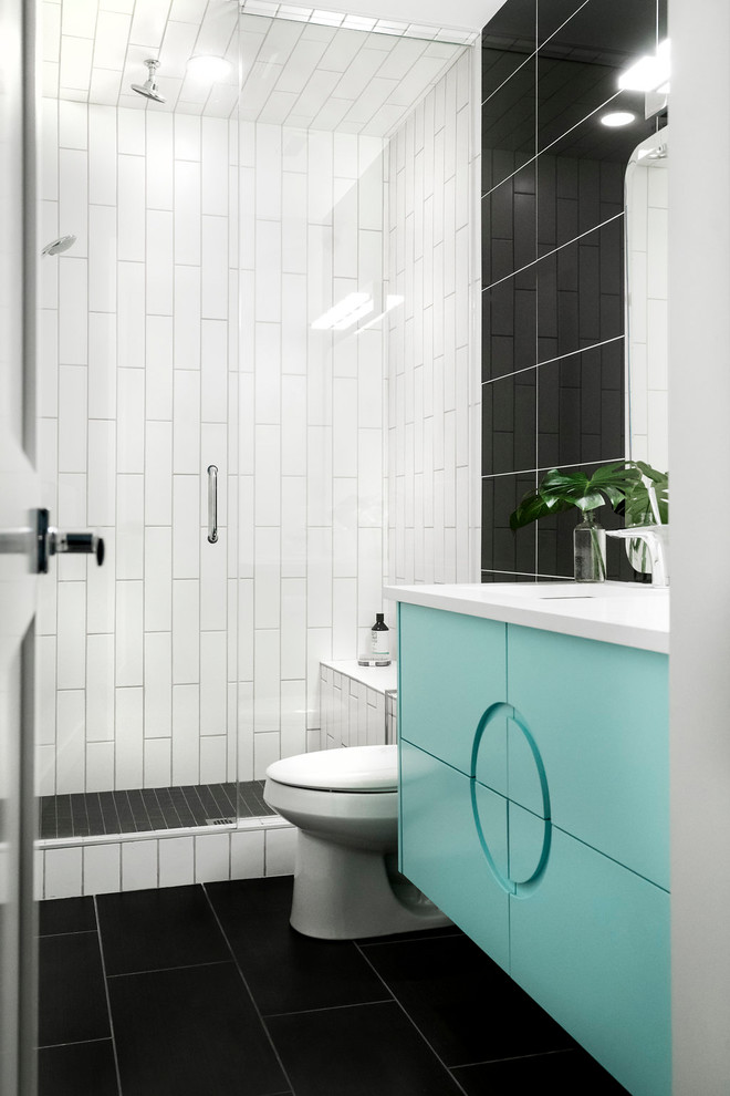 This is an example of a mid-sized midcentury 3/4 bathroom in Calgary with furniture-like cabinets, turquoise cabinets, black tile, porcelain tile, beige walls, porcelain floors, an undermount sink, quartzite benchtops, grey floor, a hinged shower door, an alcove shower, a one-piece toilet and white benchtops.